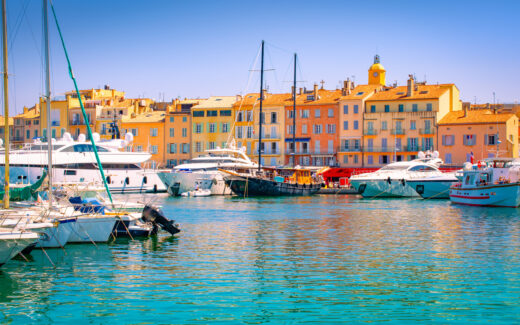 Waterfront and harbor view of St Tropez with luxury boats and yachts. Colorful image with buildings in the background.
